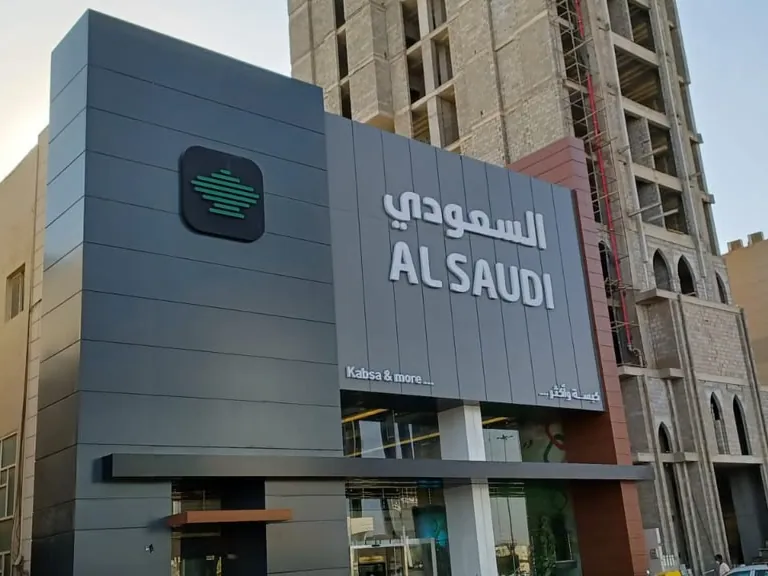 واجهة مطعم السعودي بألواح كلادينج رمادية وأحرف بارزة بالعربية والإنجليزية