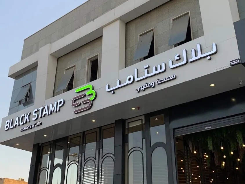 واجهة مقهى بلاك ستامب بأحرف بارزة عربية وإنجليزية وشعار أخضر