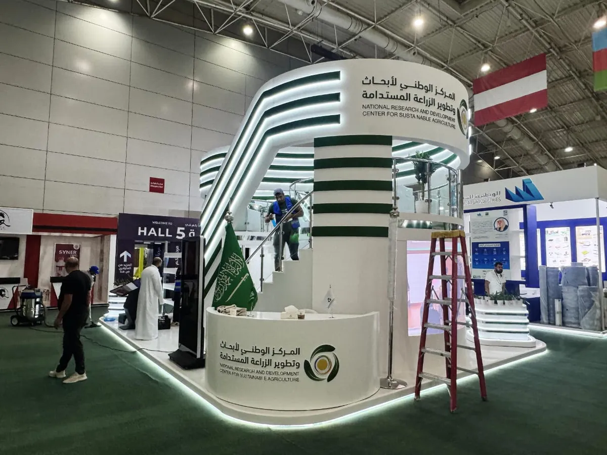 جناح المركز الوطني لأبحاث وتطوير الزراعة المستدامة بخطوط خضراء وبيضاء مضيئة في قاعة معرض
