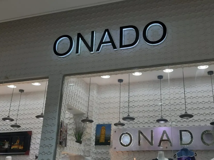 أحرف ONADO السوداء بإضاءة خلفية فوق واجهة متجر زجاجية